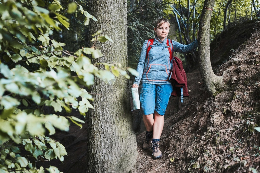 活跃妇女在森林道路上行走积极渡暑假背包持有携带流浪癖假期图片