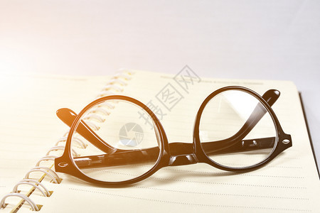 工作场所覆盖将眼镜和阅读书放在该上桌子背景图片