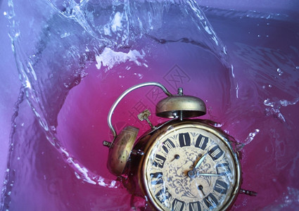 过去的步仪表古老闹钟在落下喷入水中时间的概念图片