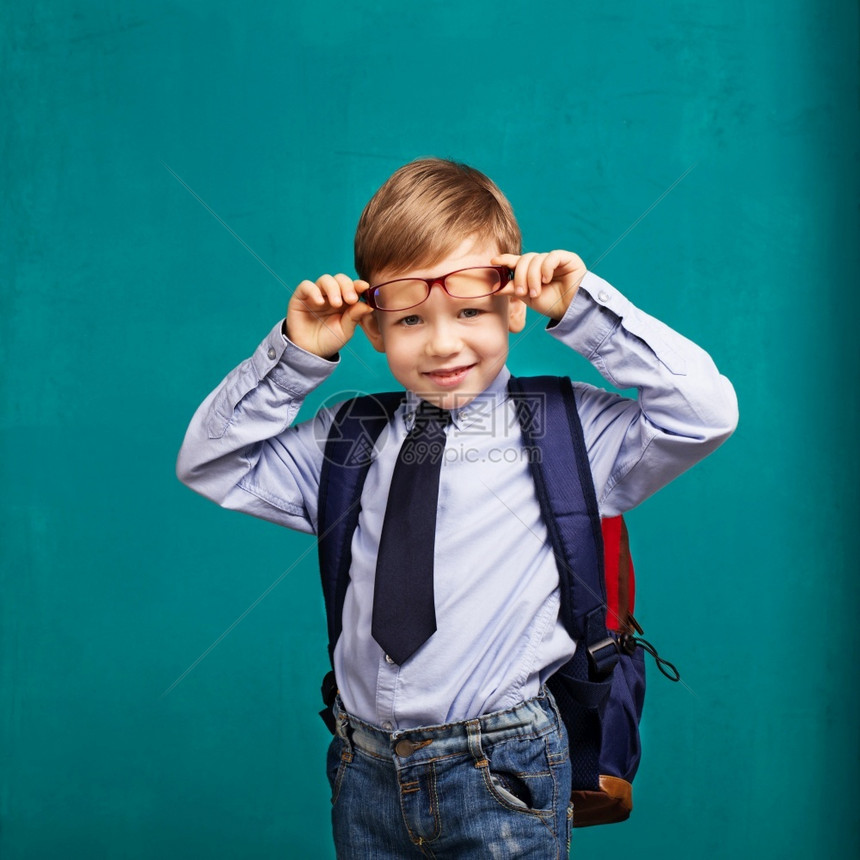 快乐的肖像后退小男孩在眼镜与大背包学校孩子rucksackback笑的小孩和黑板对着粉笔图片