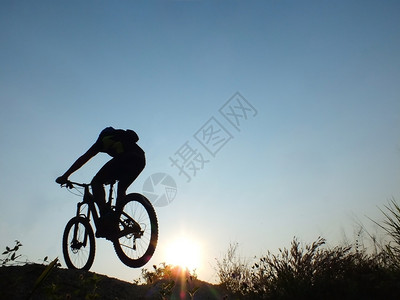 锻炼娱乐男日出山上骑自行车时的轮光图片