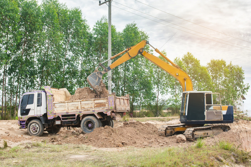 桶一种黄色挖掘机将土壤装入建筑工地的倾卸卡车中无人机图片
