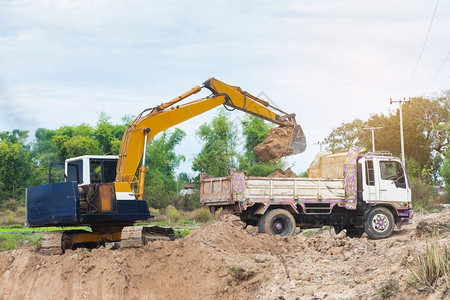 装载机天线黄色挖掘将土壤装入建筑工地的倾卸卡车中辆图片