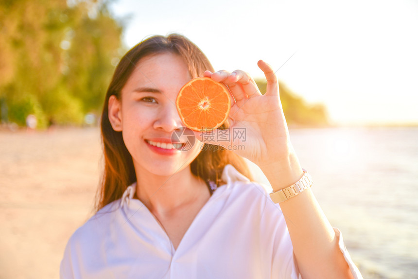 甜的在海滩背景中妇女持有橙色切片水新鲜图片