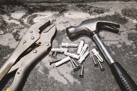 使固定职业用于修理的家工具旧钢扳手在锈水泥背景上装有塑料锚的锤子构造图片