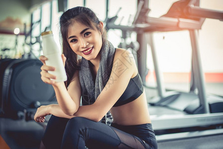 锻炼亚洲健身运动妇女休息时展示奶瓶或放松饮食料和健康概念身体育和设备主题在休息期间展示牛奶瓶的亚洲运动妇女服食物背景图片