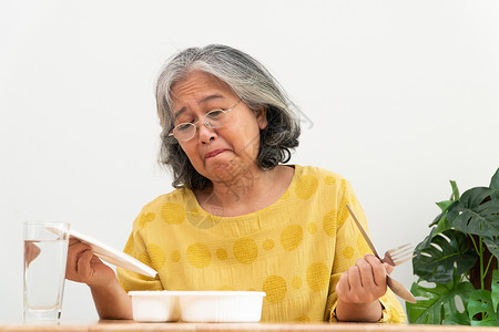 混吃等死伤心女士亚洲年长妇厌食症不高兴拒绝随时饭食老人独居无聊食物没有胃口等盘子背景