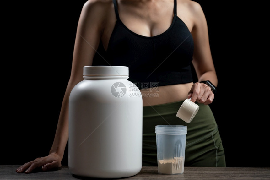 健身房手肌酸近距离接女测量一勺威士蛋白质罐子和摇晃瓶以制作蛋白奶昔图片