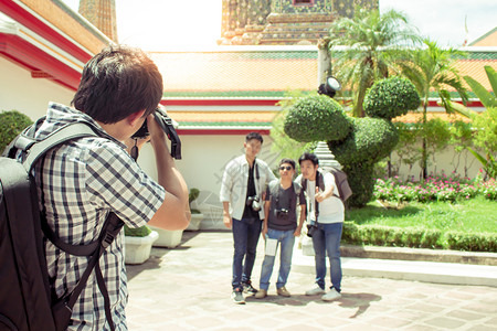 快乐的活动男游客在泰国寺庙里拿着相机拍照并朋友片黑色的图片