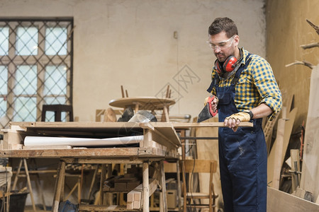 人工吹制木工专业匠用手锯制板和车间男人工背景