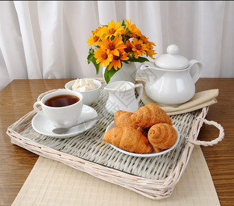 放花朵甜的早餐和牛角面包加茶餐盘上的牛奶图片