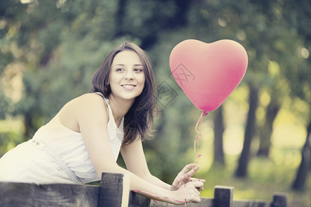 阳光树幸福快乐微笑的年轻女站在红形心气球外出门前图片