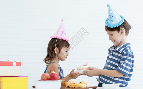 女朋友们一个天主教男孩给一个蛋糕与蜡烛给他的小妹为庆祝她的生日吃图片