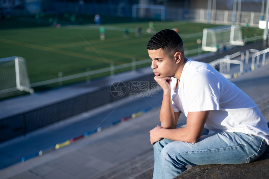 男人年轻足球迷坐在体育场的露天运动机上无聊快乐的年轻图片