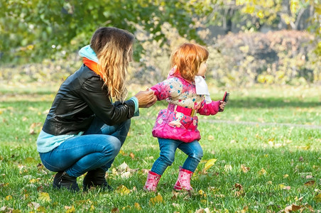不服从年轻的妈在公园里和女儿玩耍漂亮的图片