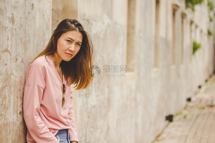 穿粉红衬衫的女士靠着旧墙吸引人的城市成图片
