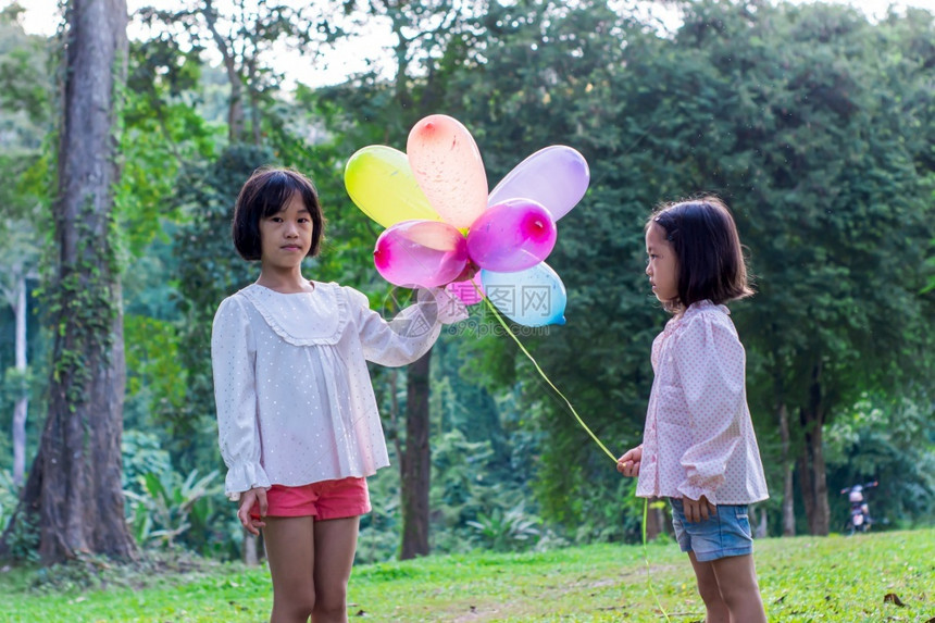 场地孩子们明亮的两名女孩在公园户外的内持有多彩玩具气球图片