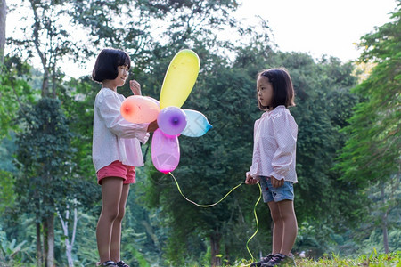 亚洲丰富多彩的乐趣两名女孩在公园户外的内持有多彩玩具气球图片