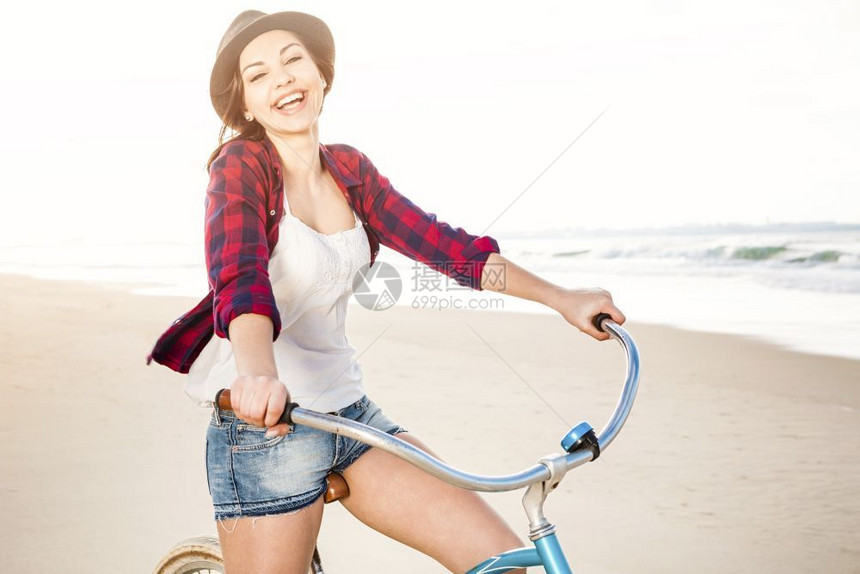 潮人微笑美丽一个有魅力的年轻女子在海滩上骑着自行车图片