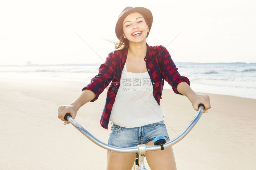 一个有魅力的年轻女子在海滩上骑着自行车美丽的放松青少年图片