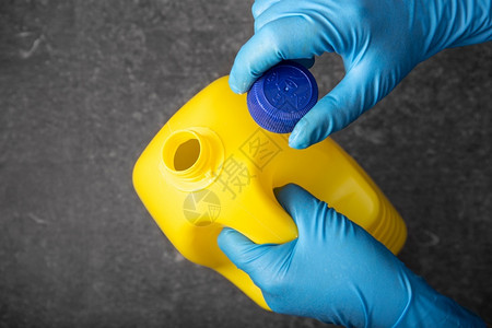漂白剂美白清洁商品家人体手戴防护套开启黄色漂白剂瓶的消毒概念背景