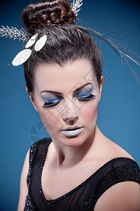 白种人睫毛膏黑褐色人女肖像穿着奢华的银色化妆品和蓝背景的发型美丽图片