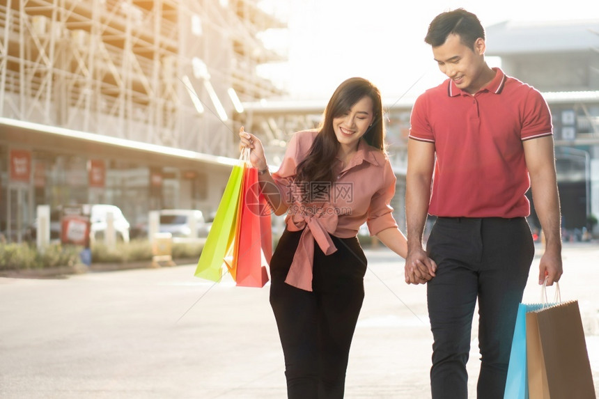快乐的年轻小买家们在购物街上走手里拿着多彩的购物袋手握着销售概念和黑色星期五购物美丽的微笑街道图片
