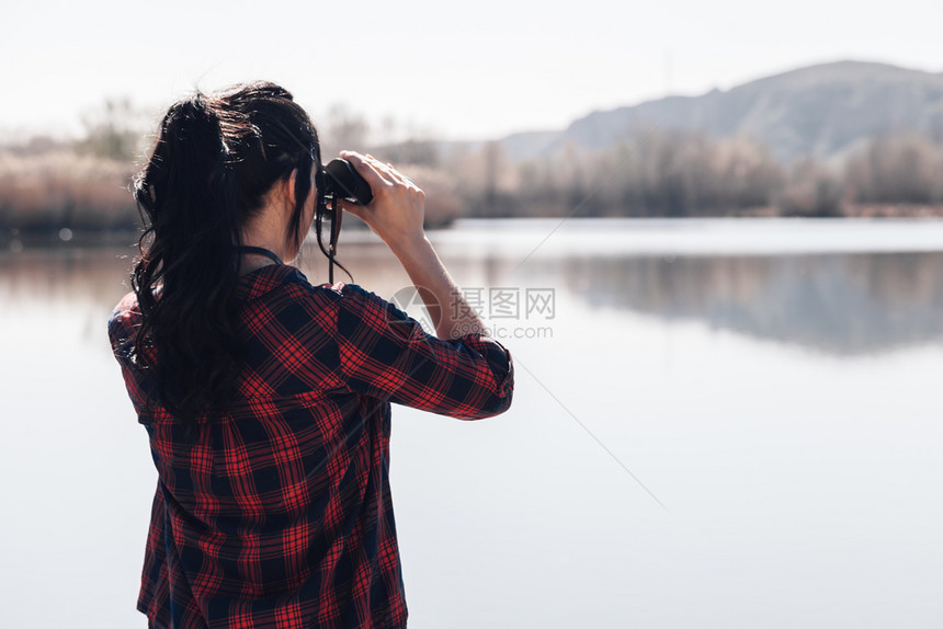 场地穿着双目望远镜和格子衬衣的湖角码头上黑发年轻女人衬衫游客图片