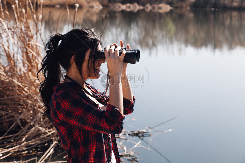 自然冒险探家穿着双目望远镜和格子衬衣的湖角码头上黑发年轻女人图片