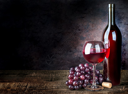 木制的浪漫黑色一杯红酒葡萄和瓶子在木制桌上一杯红酒葡萄和瓶子图片