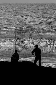 镇黑色的有两个渔民休光灯正在用长杆捕鱼老的图片