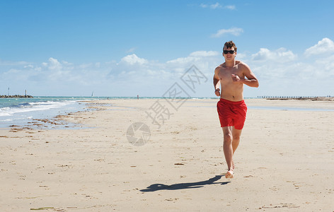 尽管去跑一个年轻人沿着海岸跑来去粗壮的成人青年背景