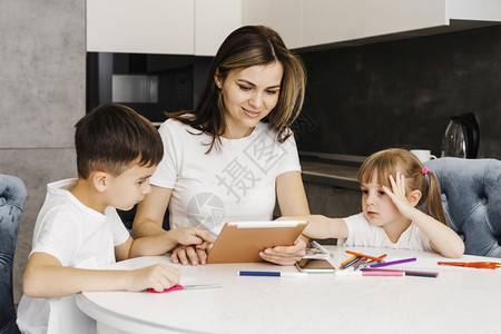 微笑随意的孩子们用数字平板电脑学习在家的子女母亲图片