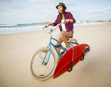 度假冲浪女子在海滩上骑自行车图片