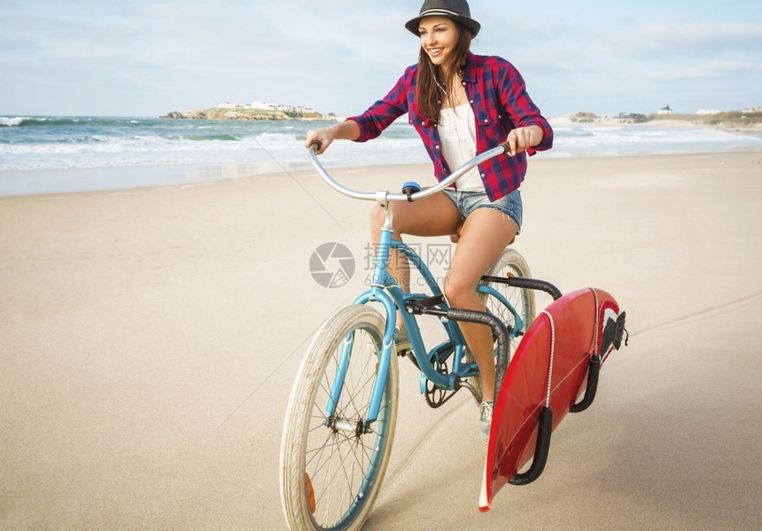年轻女子在海滩上骑自行车图片