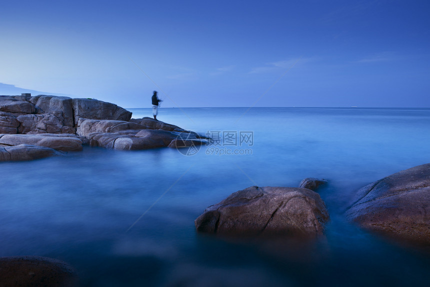 蓝色的人们与类在岩石上捕鱼一起在晨光下长距离接触蓝海户外图片