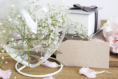 复制空间白色的木背景心脏瓶中装有吉普西拉鲜花的空白纸标签生日图片