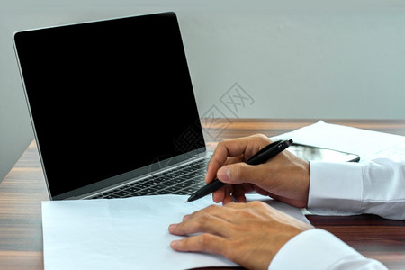 金融商人在纸质文件工作上用笔写字手文件贴近电脑公司的图片