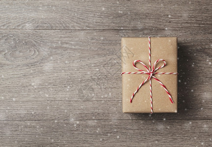 卡片棕色礼品盒的顶部视图上面有红绳贴在木背景上并有复制空间雪花十二月图片