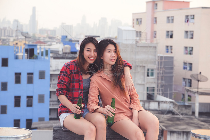 两个亚裔妇女饮酒在屋顶派对户外庆祝友谊女男双和变者夫妇微笑愉快请享用图片