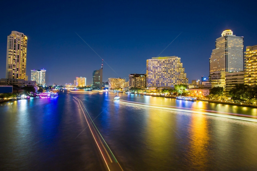 游艇在城市背景中反映水的亮光和城市背景中的淡光明亮城市景观图片