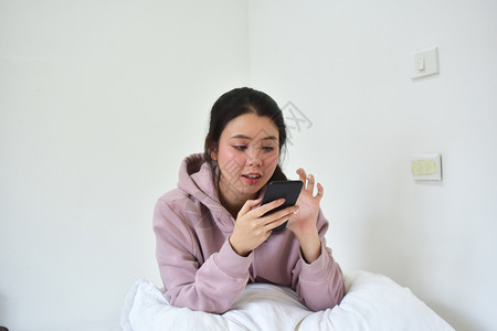 肖像聪明的可爱使用移动智能手机的妇女是离子卧室图片