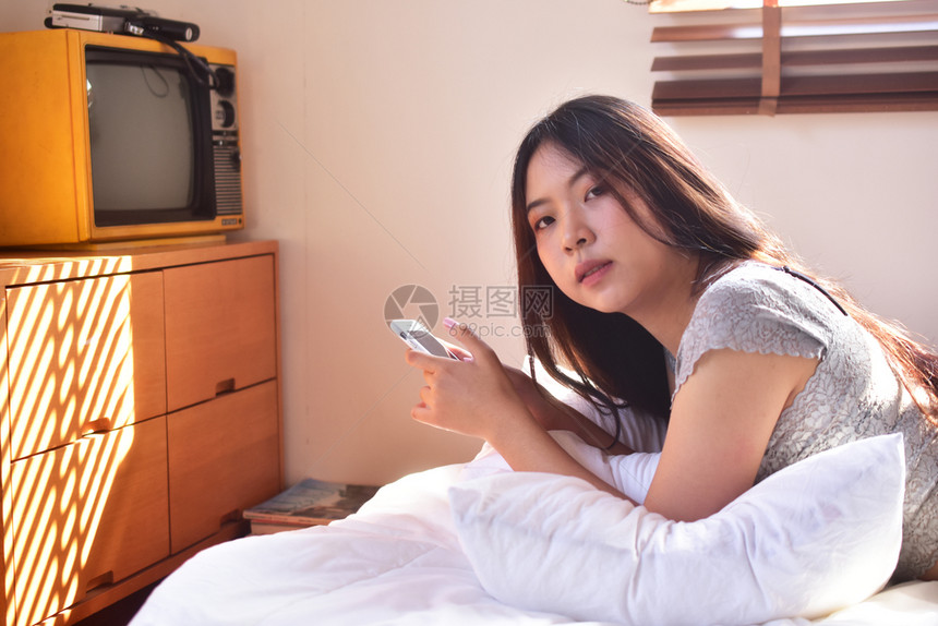 吸引人的成技术使用移动智能手机的妇女是离子卧室图片