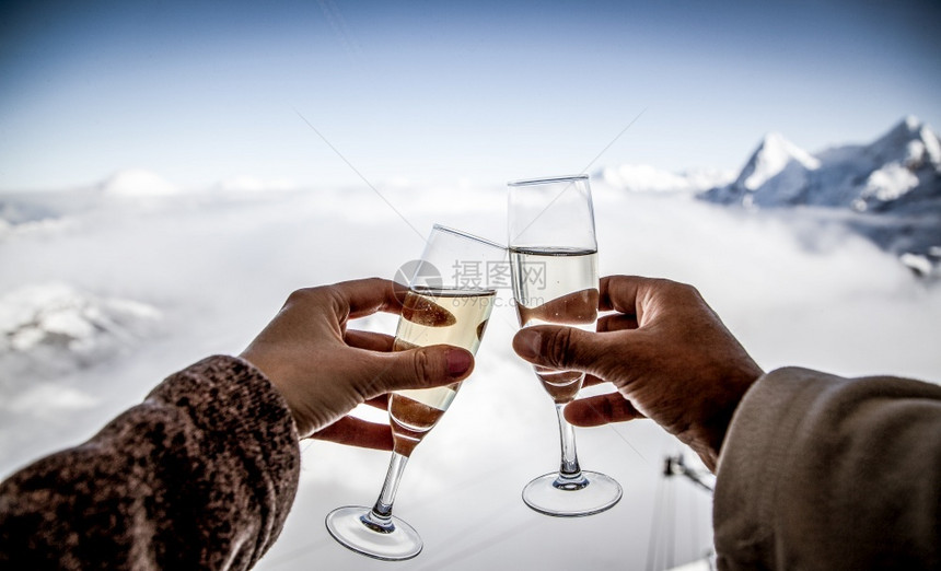 圣诞节抓住一对夫妇起喝香槟和雪山冬季假期滑雪图片