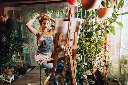 室内的专业微笑与工厂一起在作室的画布上拍摄专业女艺术家绘画的室内镜头图片
