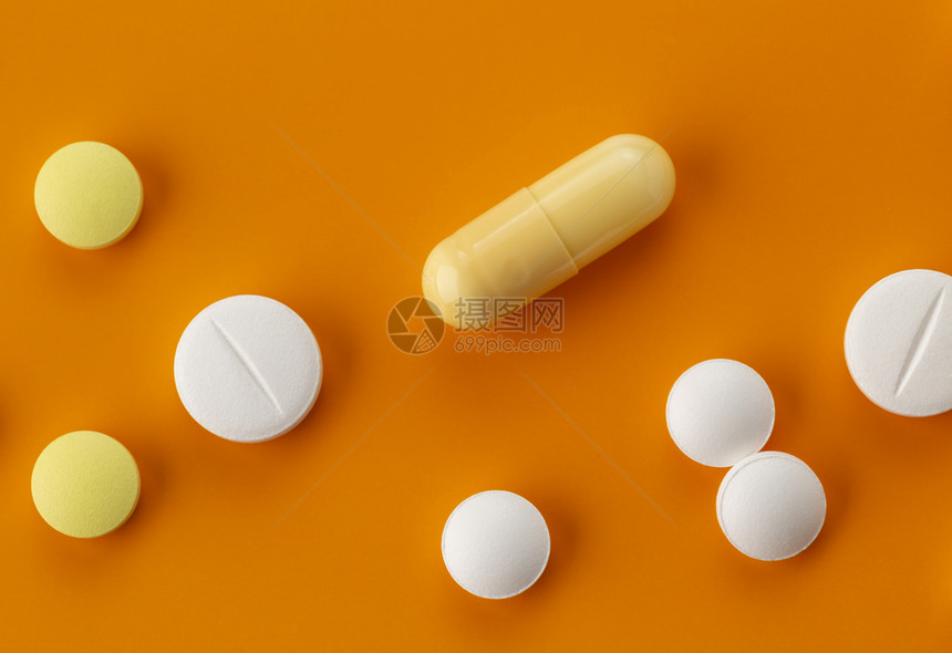 橙色背景下各种各样的胶囊药物图片