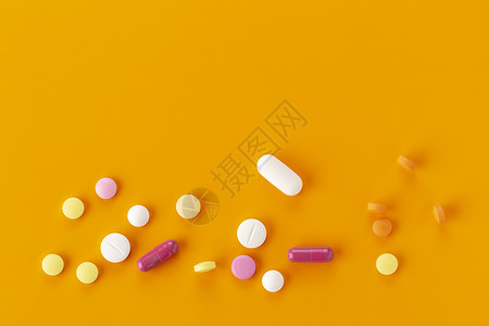 橙色背景下各种各样的胶囊药物背景图片