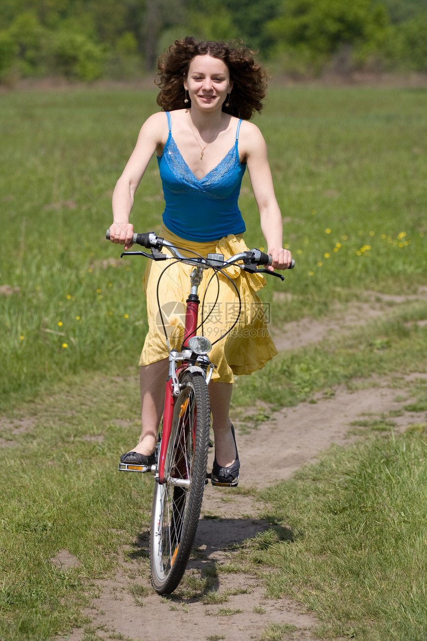 快乐的女孩骑自行车去松弛娱乐公园图片