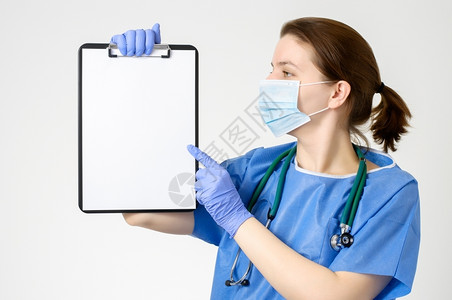 广告年轻的女士医生用空白纸指着剪贴板图片