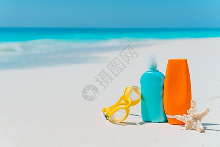 防胀气奶瓶风镜白沙滩背景的上太阳淇淋瓶护目镜海星和太阳墨镜海洋中的太阳奶瓶眼镜白沙滩上的海星晴天皮肤背景